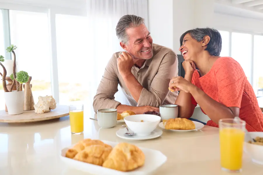 A couple smiling together as they make breakfast at home