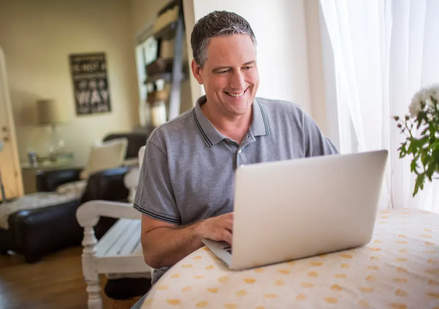 A man reading carefully on his laptop at home
